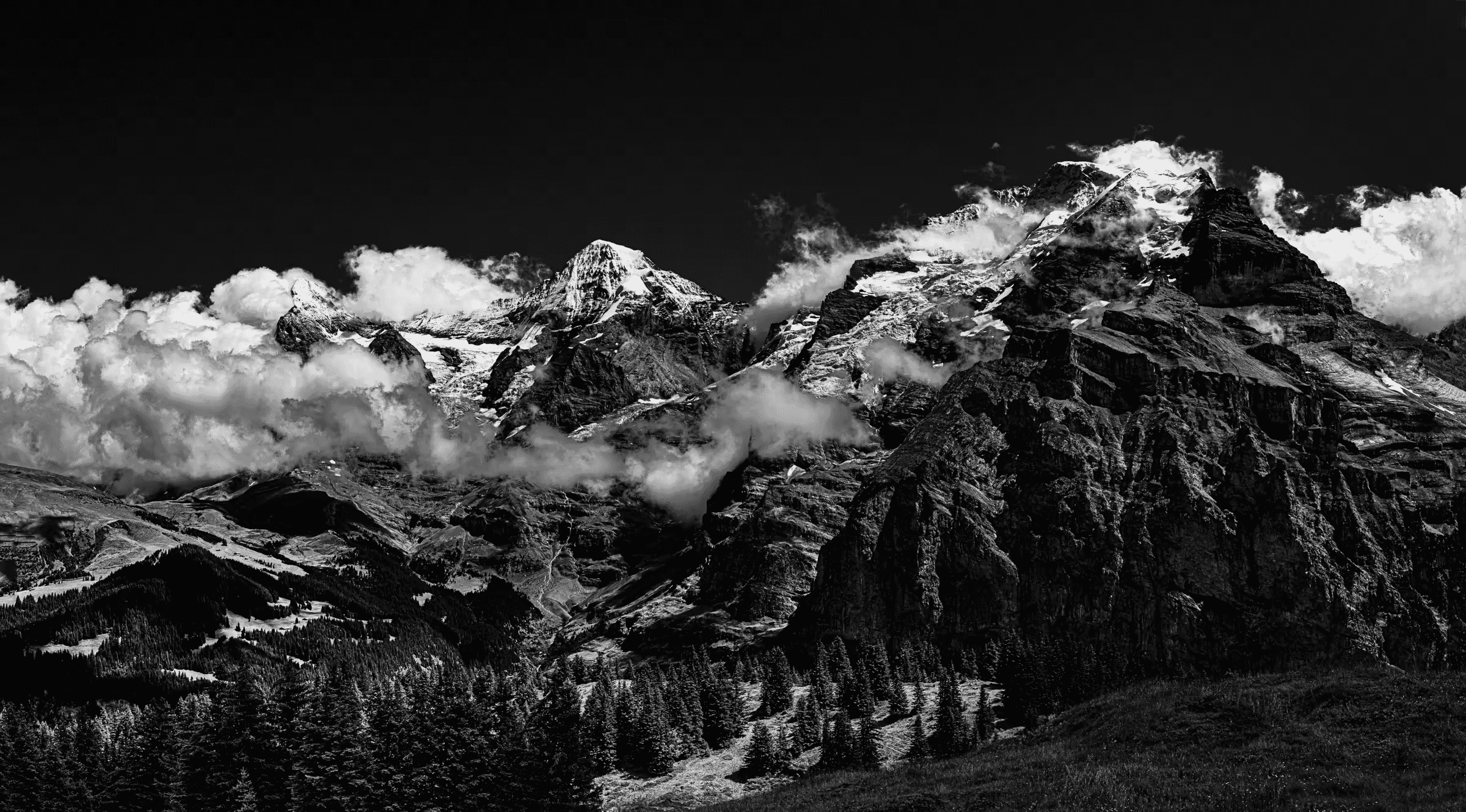 Black and white landscape photograph of the Eiger, Mönch, and Jungfrau mountains in the Swiss Alps, viewed from Mürren.