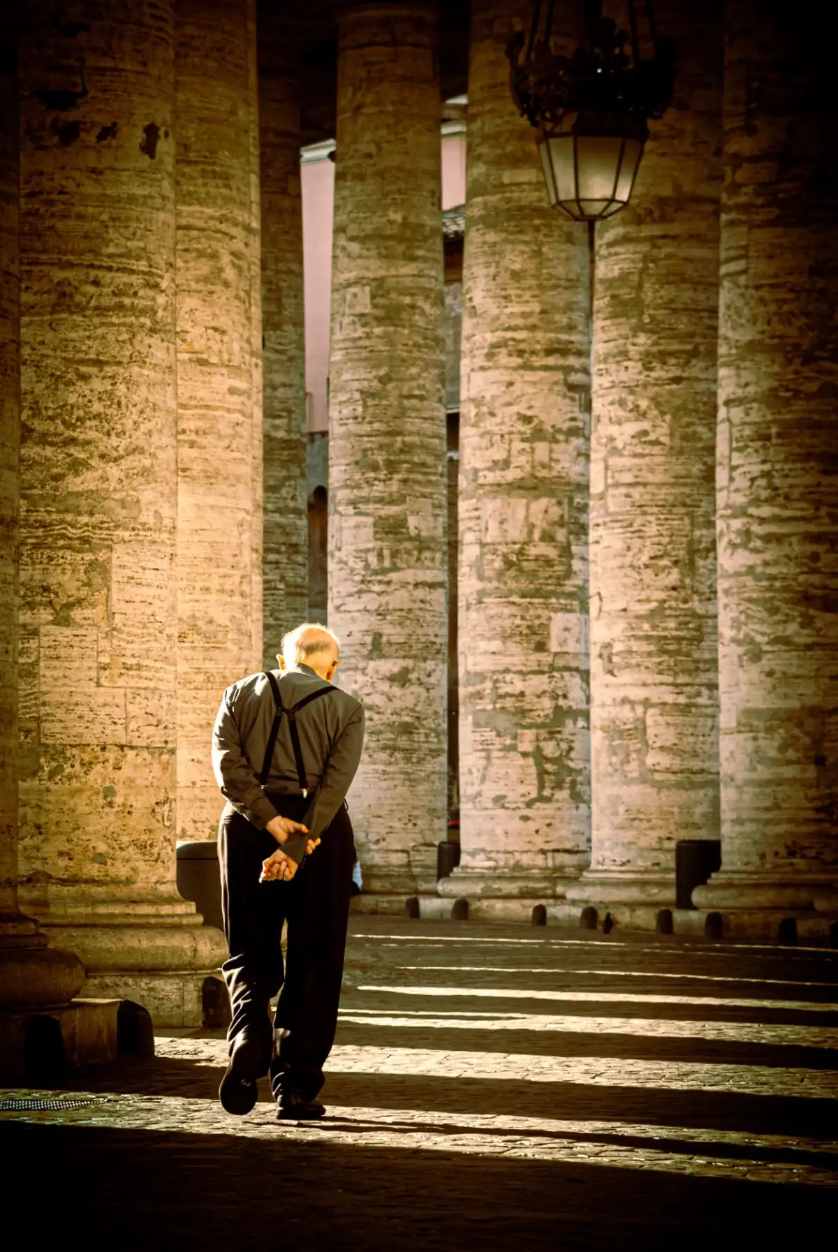 Old priest doing the walk under the arches