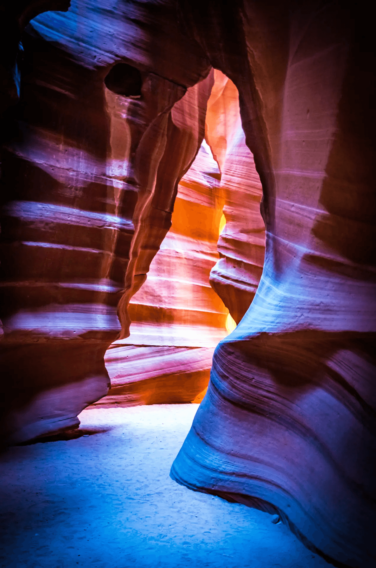 Antelope Canyon, Arizona, landscape photograph. Sunlight filters into a slot canyon, illuminating the sculpted, wavy sandstone walls in warm hues of orange, red, and purple. Dramatic light and shadow play highlights the canyon's textures and forms. Evocative desert nature photography.