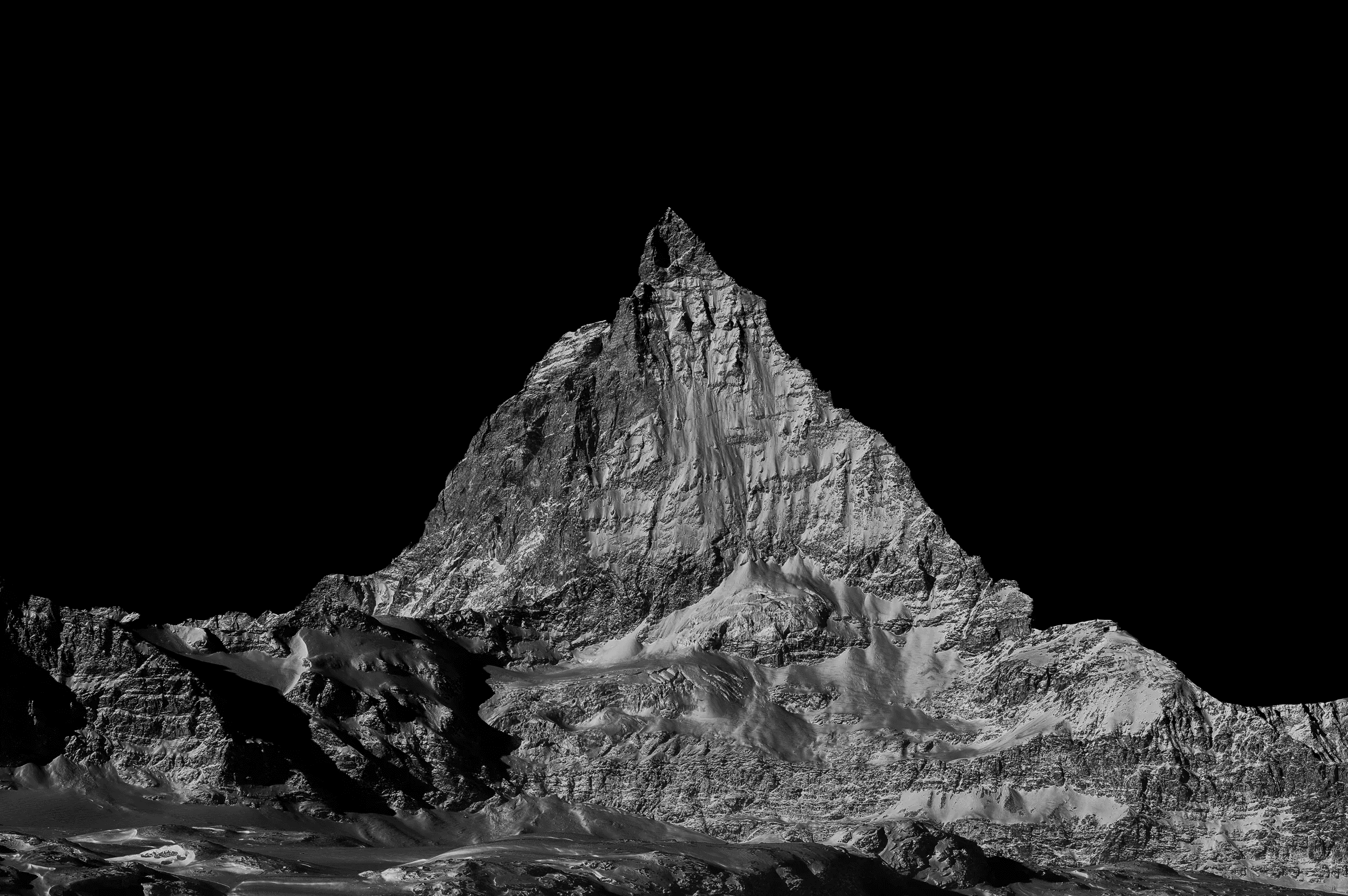 Dramatic black and white photograph isolating the iconic, snow-dusted peak of the Matterhorn against a dark sky.