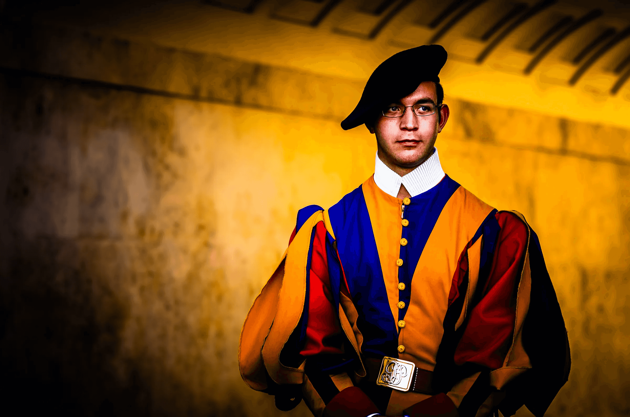 Color portrait of a Swiss Guard standing duty in Vatican City, wearing the traditional colorful Renaissance uniform and black beret.