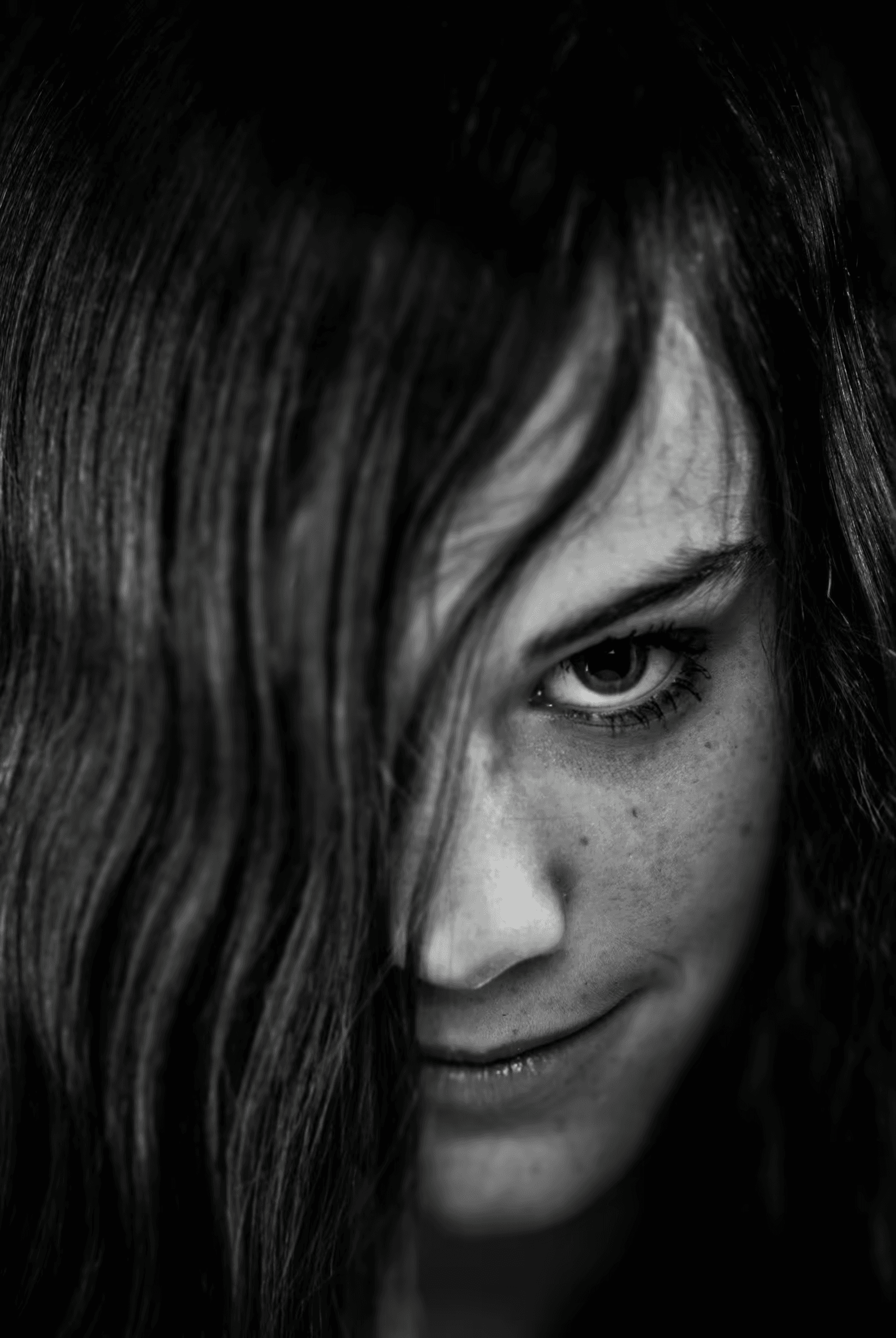 Hidden Gaze: Monochrome Portrait Black and white portrait of a woman with long hair partially covering her face.